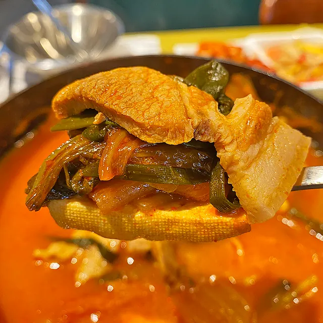 현주식당 김치찌개에서 돼지고기와 김치를 국자로 들어 올린 모습