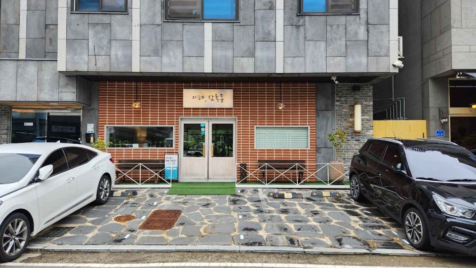 카페 삼룡동 간판과 벽돌 외벽, 건물 앞 주차 공간