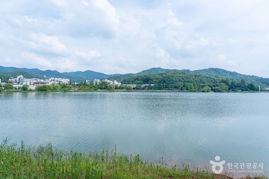 넓은 호수 수면 너머 건물과 낮은 산이 보이는 천호지 전경