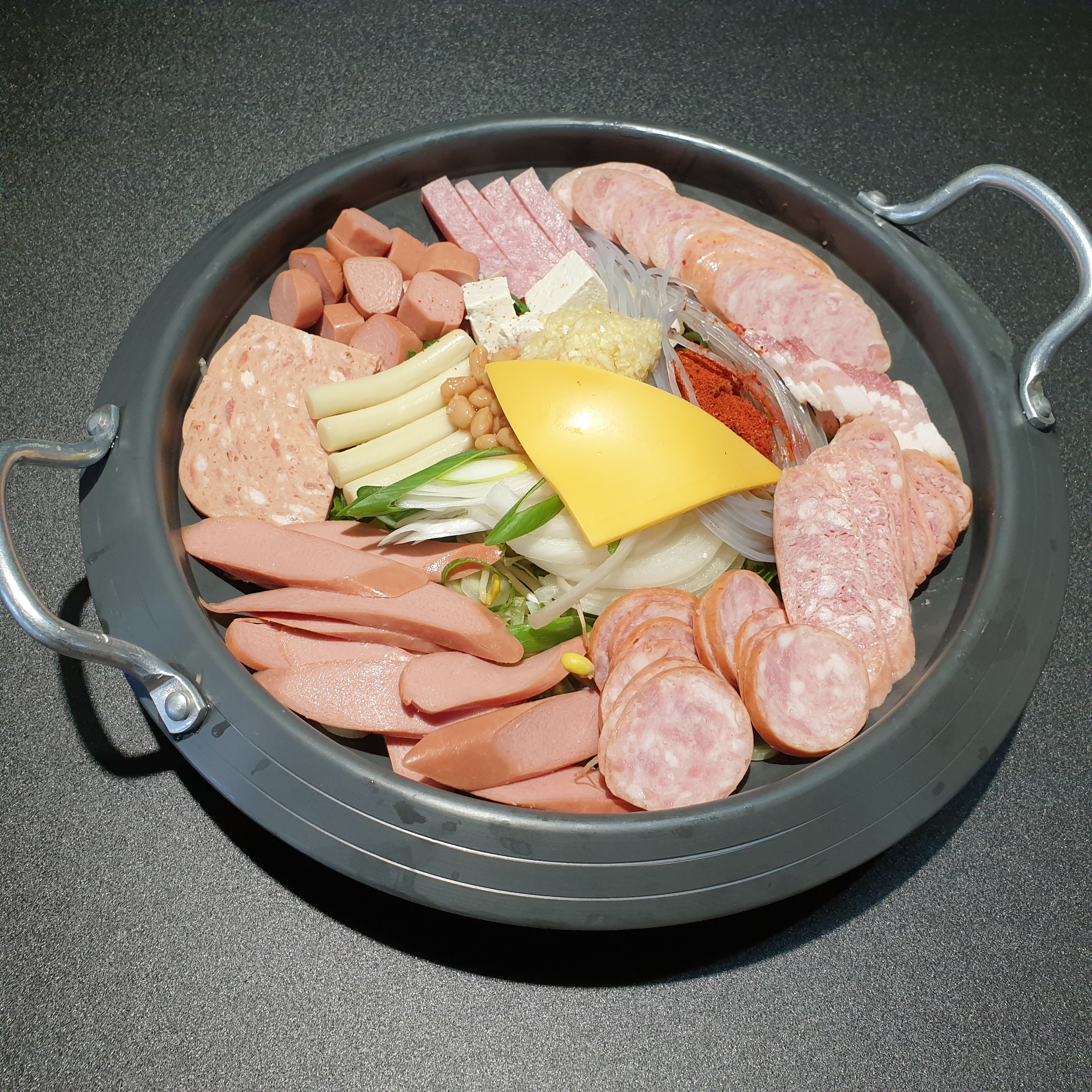 상근이부대찌개 메뉴에 실린 햄과 소시지, 치즈가 담긴 냄비