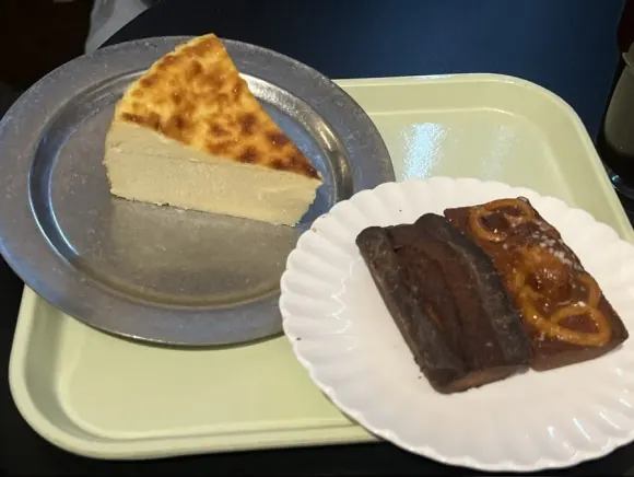 접시에 담긴 프로바이드 치즈케이크 한 조각과 휘낭시에 두 개