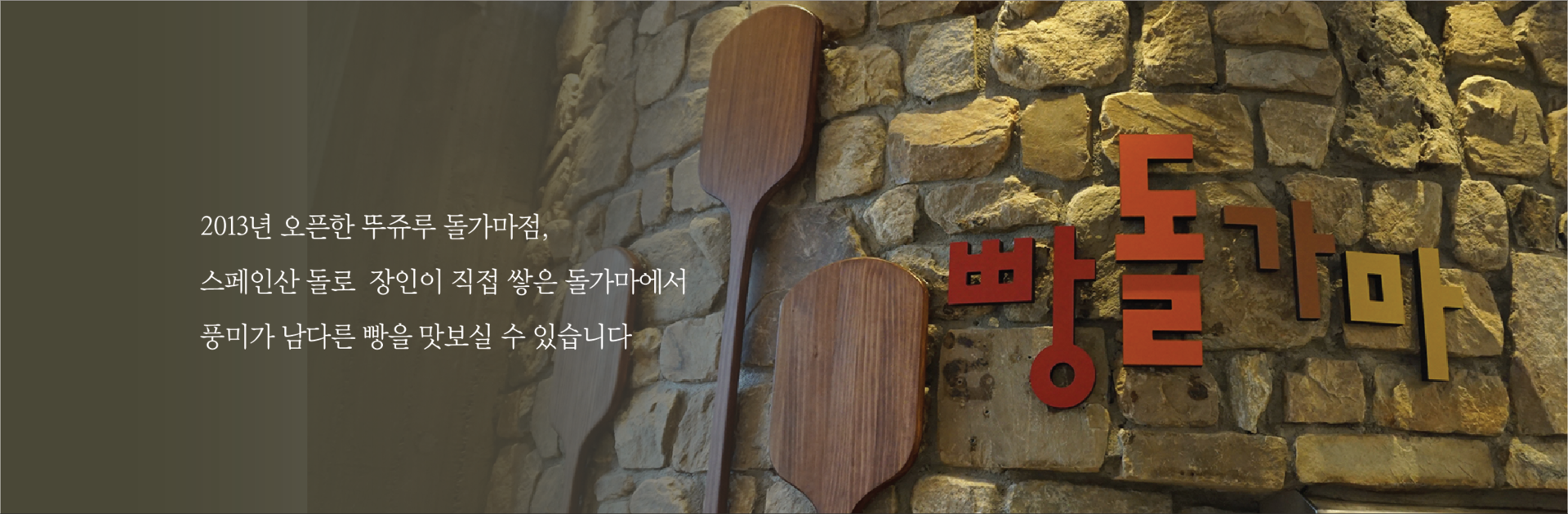 돌벽에 붙은 빵돌가마 글자와 나무 주걱 장식, 왼쪽의 공식 소개 문구 · 자료사진
