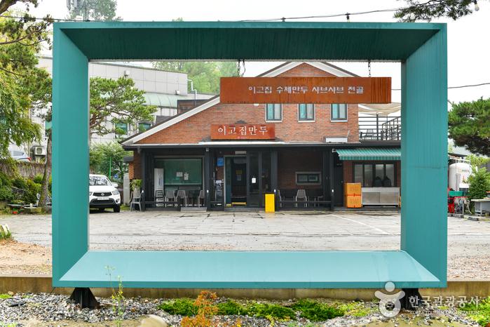 초록색 사각 프레임 너머 이고집만두 간판과 빨간 벽돌 외관