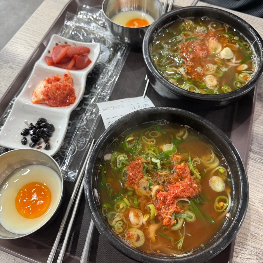 국밥 두 그릇과 별도 계란 그릇, 반찬이 담긴 식사